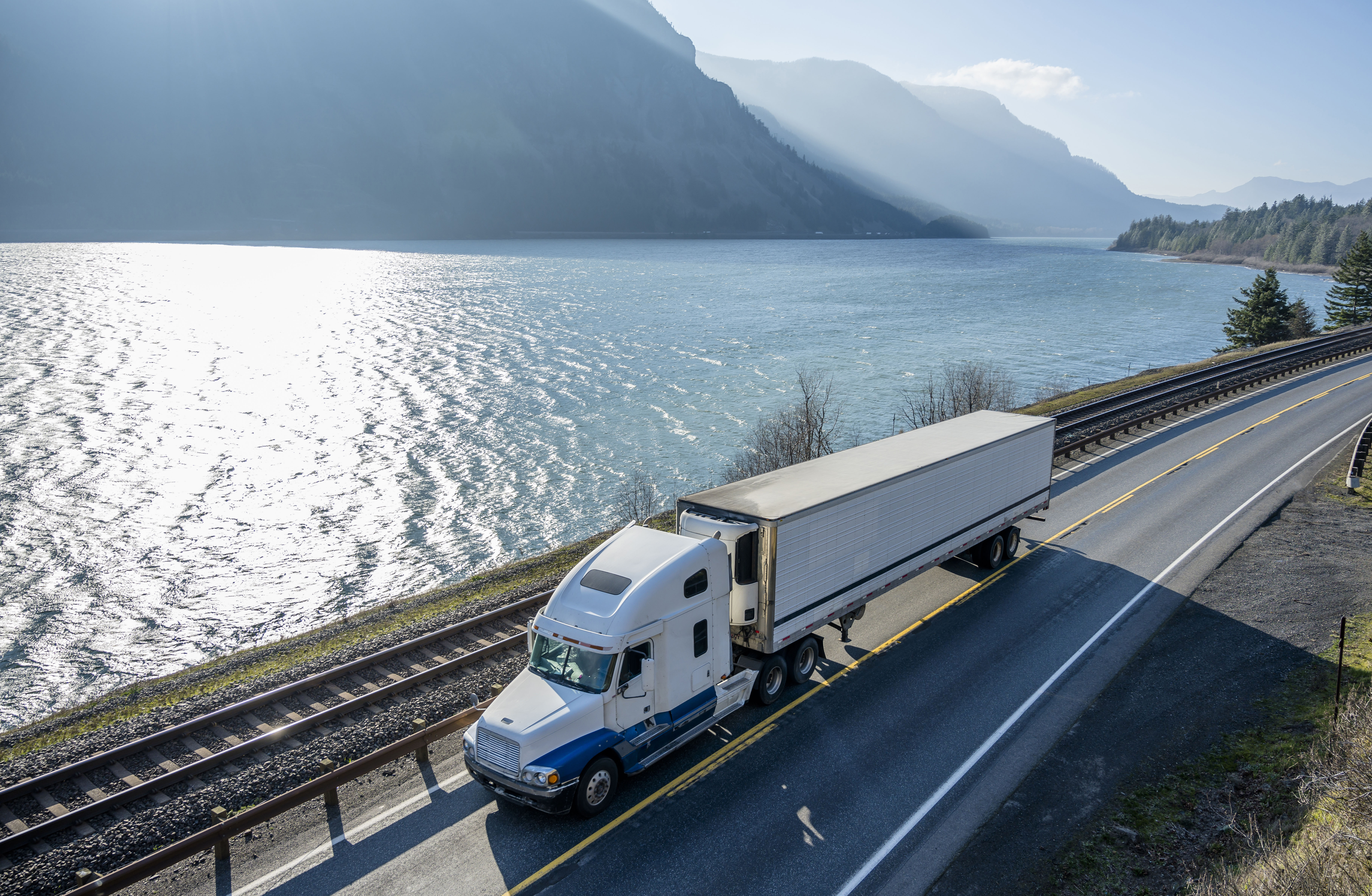 Big rig semi truck transporting cargo in refrigerator semi truck running on the road along Columbia River